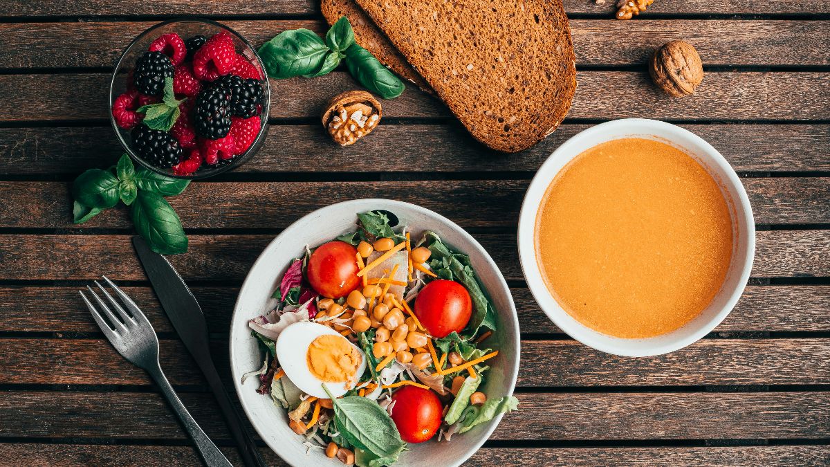 Gesunde Mahlzeit mit Salat, Beeren, Suppe und Vollkornbrot als Symbol für anti-entzündliche Ernährung und bessere Eizellqualität