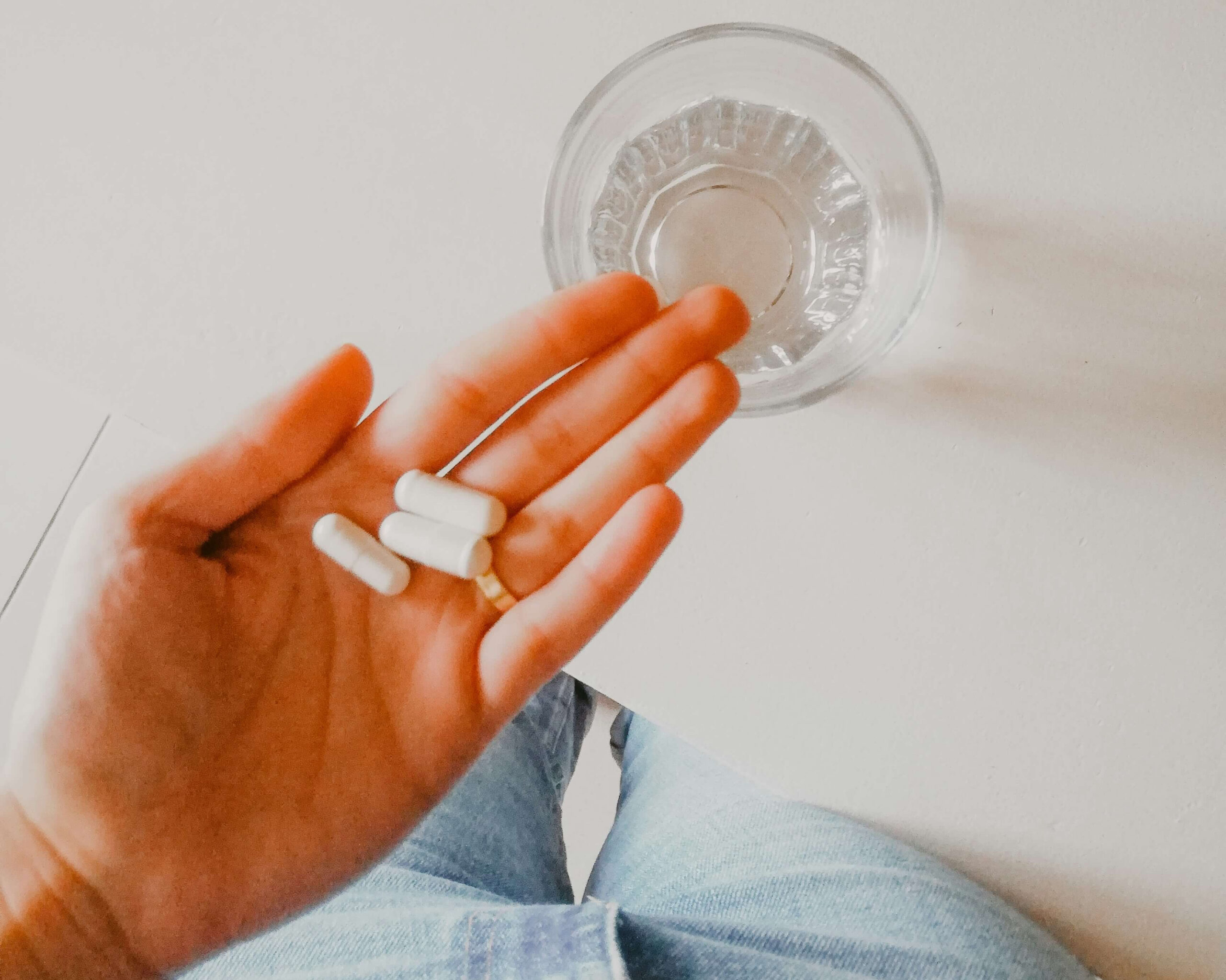 Hand mit Nahrungsergänzungsmitteln wie CoQ10 Kapseln zur Unterstützung der Eizellqualität im Kinderwunsch