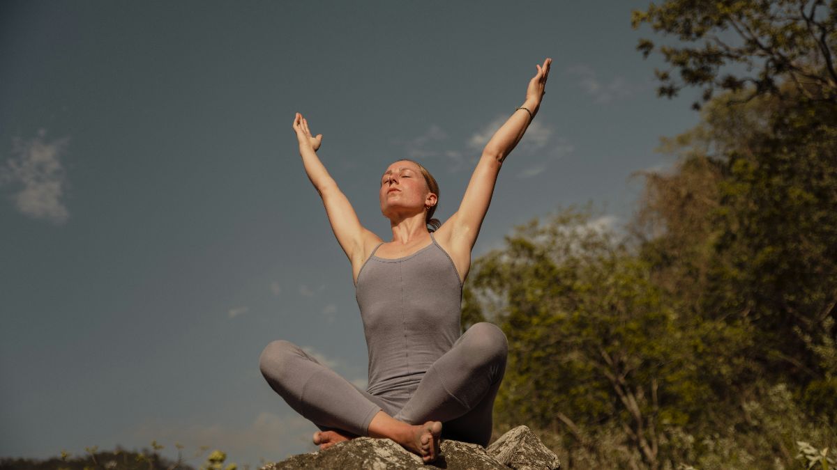 Frau sitzt meditierend im Freien als Symbol für Entspannung, Einnistung und Kinderwunsch