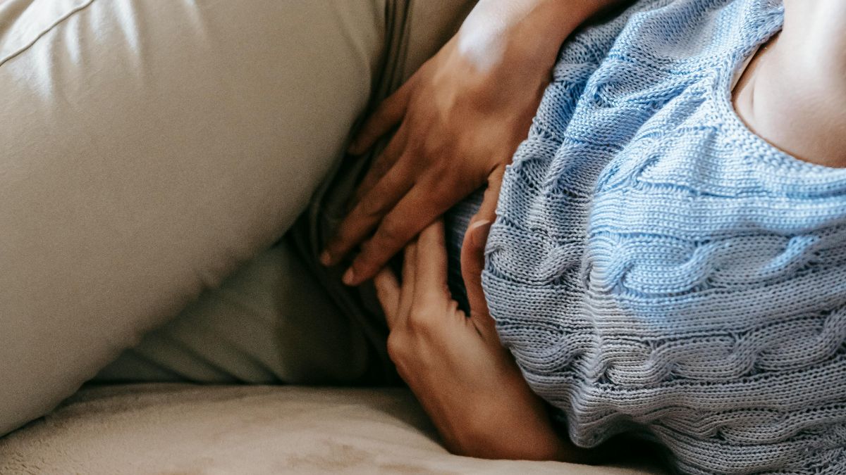 Frau hält sich den Unterbauch als Symbol für Endometriose, Adenomyose und Kinderwunsch