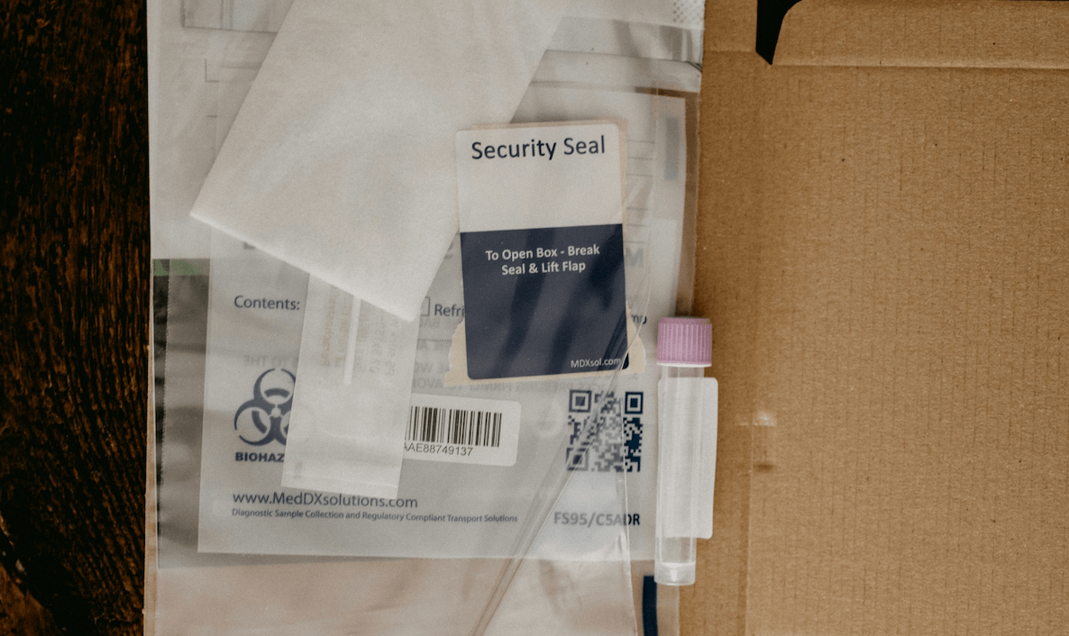 Geöffneter Versandkarton mit Probenröhrchen, Versandmaterial und Testkit für einen Fruchtbarkeits- oder Heimtest.