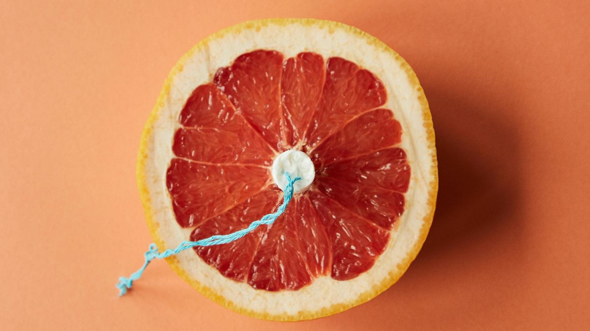 Halbe Grapefruit mit Tampon als symbolisches Bild für Menstruation, Frauengesundheit und Menstruationsblut in der Forschung