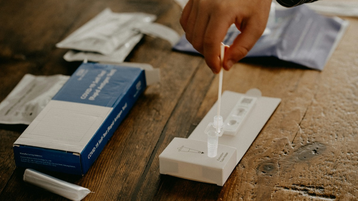 Frau sitzt am Küchentisch und führt einen Heimtest durch.