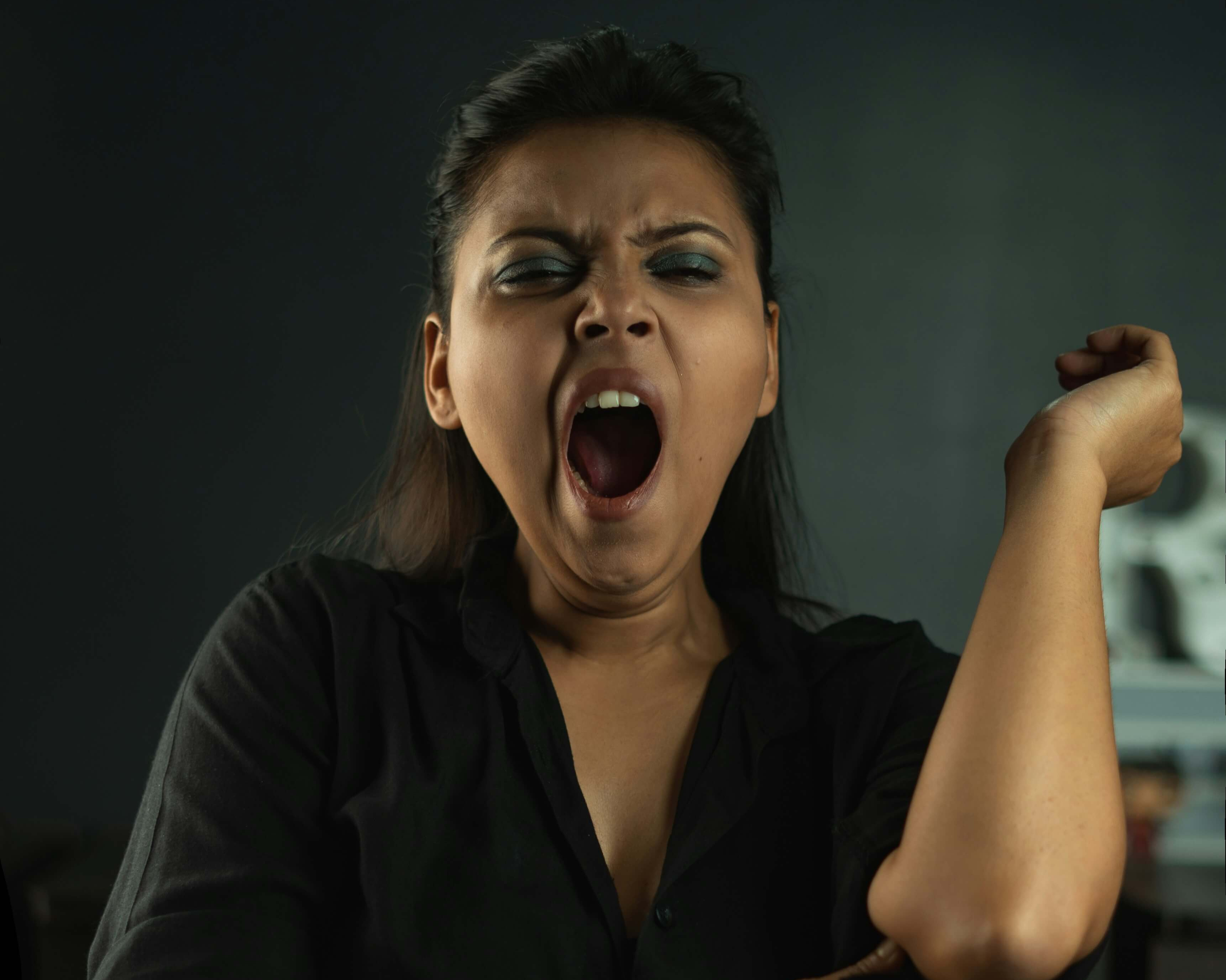 Müde Frau gähnt und wirkt erschöpft durch Schlafmangel.