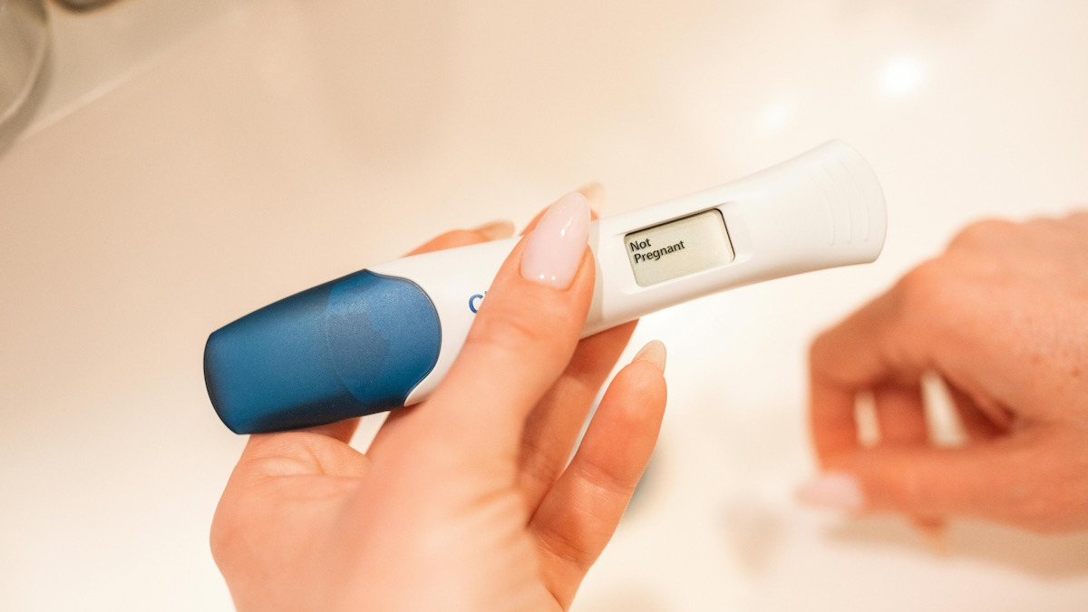 Hand hält einen digitalen Schwangerschaftstest mit negativem Ergebnis