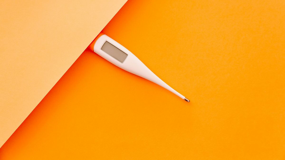Digitales Thermometer auf orangem Hintergrund für die Basaltemperaturmessung
