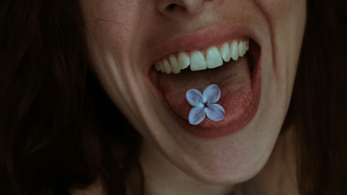 Frau mit Blüte auf der Zunge – symbolisch für den neuen Endometriose-Speicheltest als nicht-invasive Alternative zur Laparoskopie