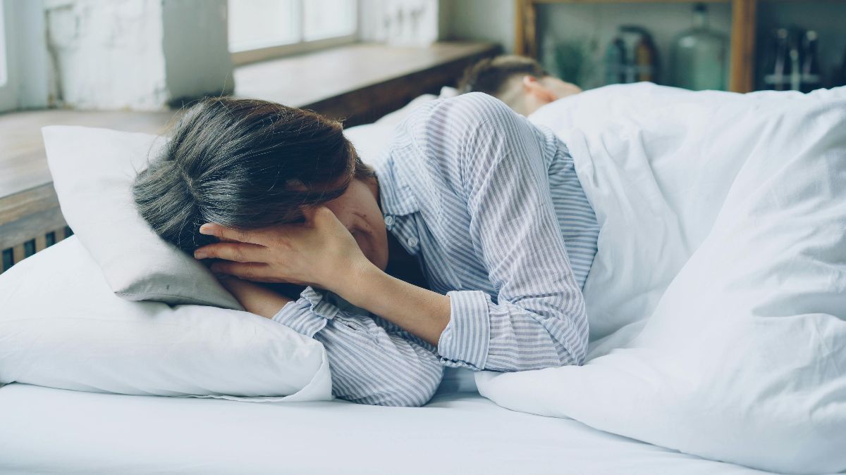Müde Frau im Bett als Symbol für Melatonin, Schlaf, Eizellqualität und Kinderwunsch