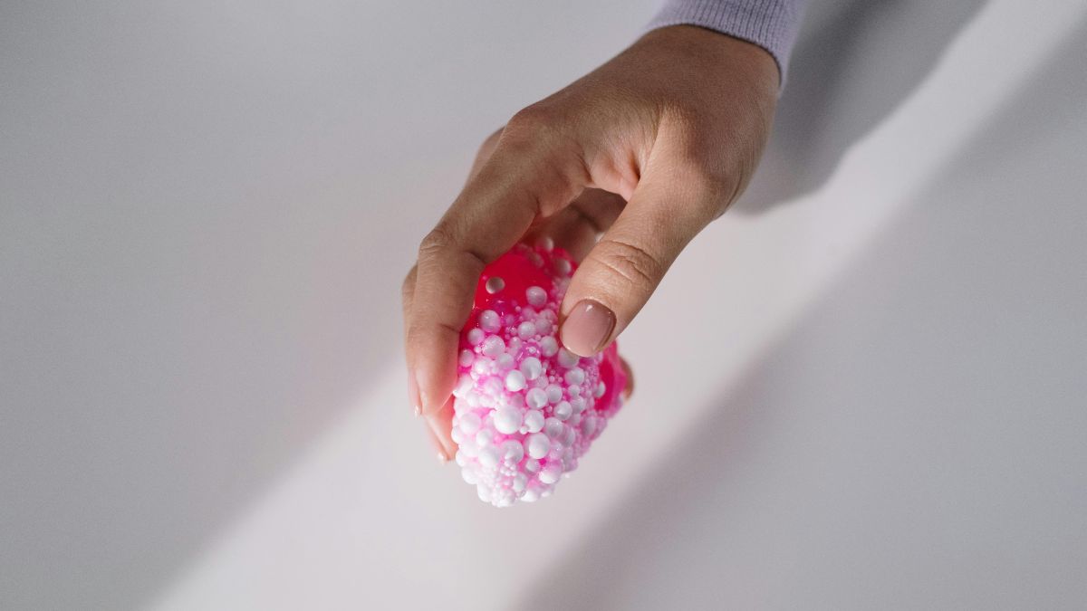 Hand hält rosa Stressball mit weißen Perlen – symbolisch für polyzystische Ovarien und die neue PMOS-Klassifizierung
