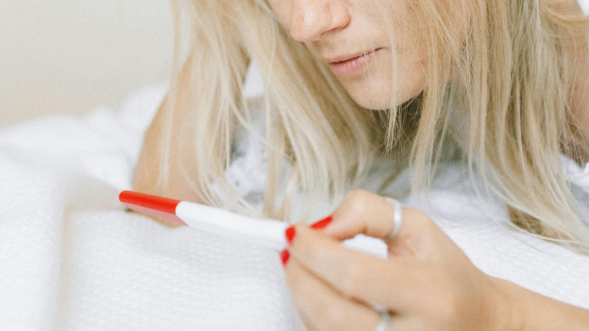 Frau schaut konzentriert auf Schwangerschaftstest – Verdunstungslinie oder echtes positives Ergebnis deuten