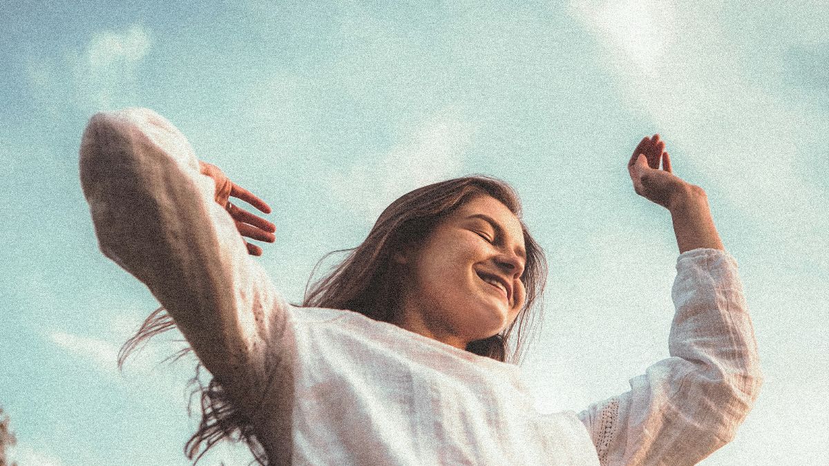 Frau streckt glücklich die Arme aus vor blauem Himmel – symbolisch für Empowerment und Lebensfreude beim Kinderwunsch ab 35