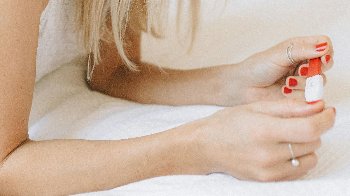 Hände einer Frau halten einen Schwangerschaftstest – symbolisch für den unerfüllten Kinderwunsch trotz unauffälliger Befunde