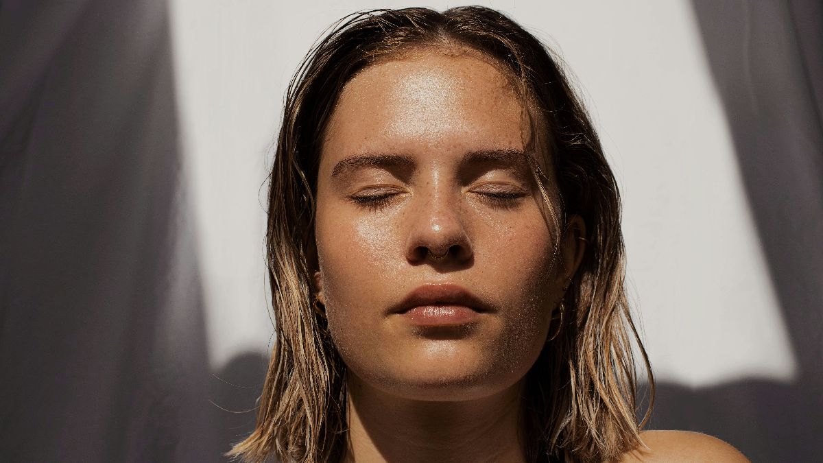 Frau mit geschlossenen Augen im Sonnenlicht – Vitamin D durch Sonneneinstrahlung als wichtiger Faktor für Einnistung und Fruchtbarkeit beim Kinderwunsch