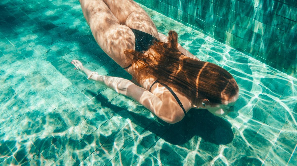 Frau schwimmt unter Wasser – moderater Sport wie Schwimmen kann die Fruchtbarkeit beim Kinderwunsch unterstützen