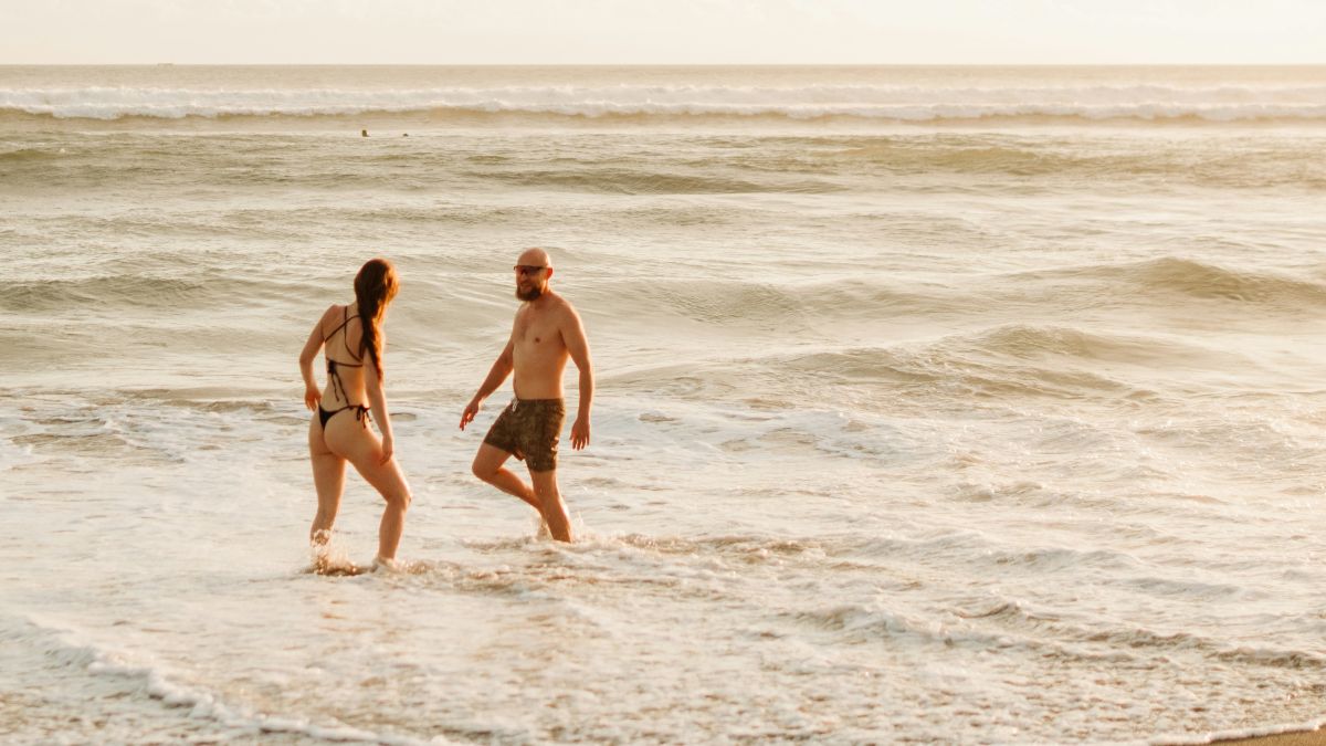 Paar geht im Meer spazieren – wie Sommerhitze die Fruchtbarkeit beeinflusst und wie man Spermien und Eizellen bei Hitze schützt